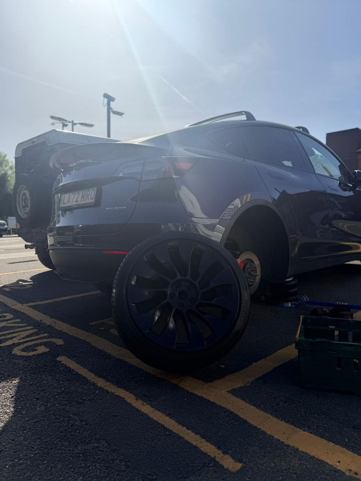 Electric vehicle mobile tyre fitting with the rear wheel removed and service equipment beside the car